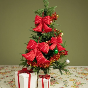 Detail of red velvet Christmas bows with gold patterns hanging on a decorated tree