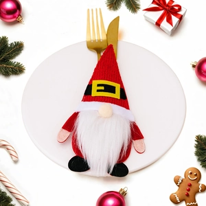 Christmas gnome cutlery holder with red hat and white beard on a decorated table