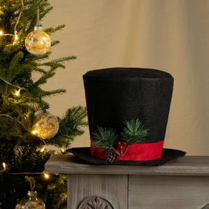 Detail of Christmas tree topper black top hat with red ribbon, pine cones and berries
