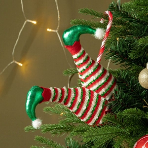 Detail of Christmas elf legs decoration with red stripes on a festive pine tree branch
