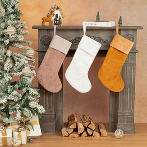 Trois chaussettes de Noël en peluche rose et blanche suspendues sur une cheminée vintage