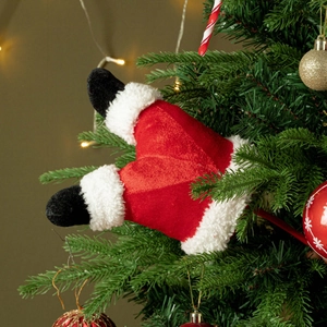 Plush Santa legs sticking out of a decorated Christmas tree with festive ornaments