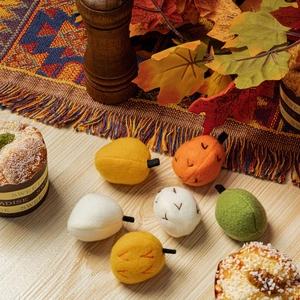 Handmade felt pumpkin and nut ornaments in autumn colors on a wooden table setup