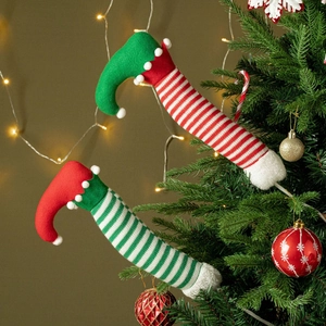 Detail of plush Christmas elf legs with red and green knit stripes stuck in a tree