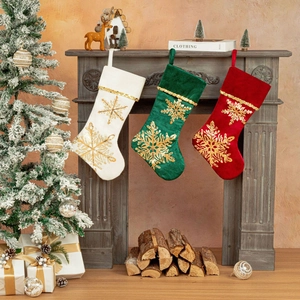 Trois chaussettes de Noël en velours avec flocons dorés suspendues à une cheminée rustique