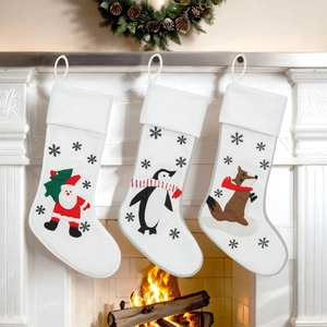 Set of 3 white Christmas stockings with Santa, penguin, and fox embroidery on a fireplace
