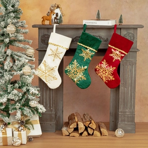 Trois chaussettes de Noël en velours avec flocons dorés sur une cheminée festive