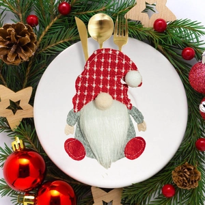 Gnome cutlery holder on white plate with pine branches and Christmas decor