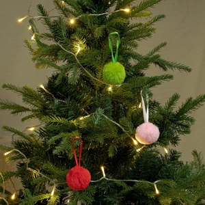 Gros plan d'ornements de pompons rouges roses et verts avec rubans sur un sapin de Noël