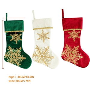 Trois chaussettes de Noël en velours rouge, blanc et vert avec des flocons dorés