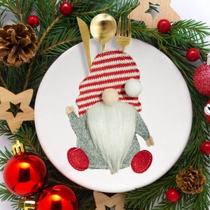 Festive gnome cutlery holder on white plate with pine branches and red ornaments