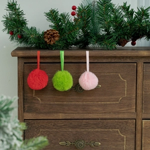 Trois ornements de Noël en pompon peluche avec rubans sur fond bois festif