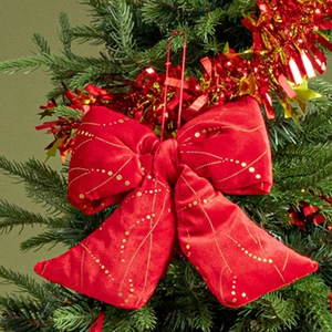 Fiocco natalizio in velluto rosso con paillettes dorate appeso all'albero verde
