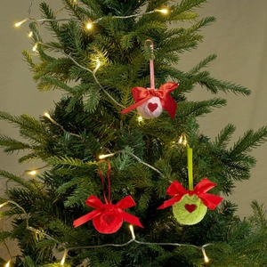 Gros plan d'ornements de Noël en peluche avec motifs cœurs et nœuds en satin sur sapin