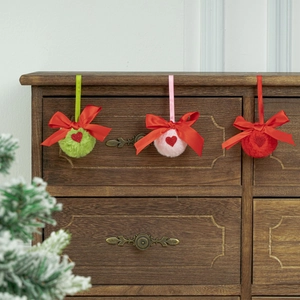Détail de pompons de Noël en peluche avec nœuds rouges sur une étagère en bois