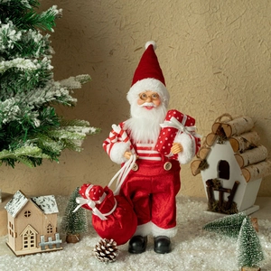 Detailed view of standing Santa Claus doll with red gift box in festive snow scene