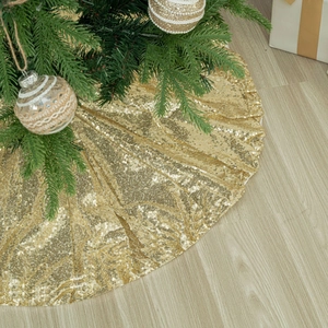 Luxurious gold sequin Christmas tree skirt on wooden floor with festive ornaments