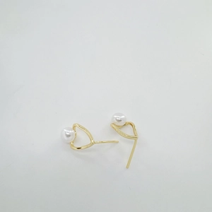 Minimalist geometric gold drop earrings with white round pearls on a white surface
