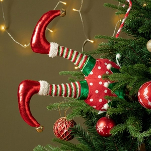 Whimsical Christmas elf legs ornament with striped fabric and bells in a pine tree