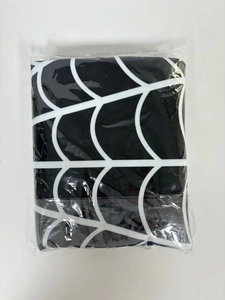 Detailed close-up of a folded black Halloween tree skirt with a white spider web pattern