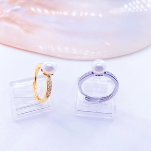 Adjustable twist pearl rings in gold and silver finish with zircon accents on shell background