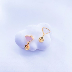 Close-up of gold-plated fan-shaped earrings with white shell and hollow flower pendant