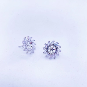 Detalle de pendientes de flores con circonitas de corte baguette en tono plateado