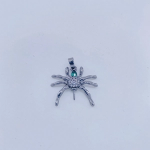 Vista macro de colgante de araña con circonitas blancas y gema verde sobre metal plateado