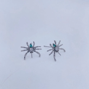 Vista detallada de pendientes de araña con piedras verdes y acabado en metal gris oscuro