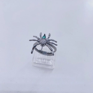 Detalle de anillo de araña gótica con gema verde y circonitas blancas brillantes