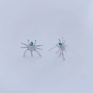 Vista detallada de pendientes de araña con piedras de color verde esmeralda y cristales