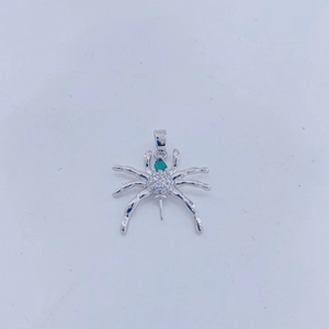 Vista detallada de un colgante de araña plateado con una piedra preciosa de color verde