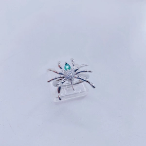 Detalle macro de un anillo de araña con piedra verde pera y cristales transparentes