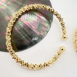 Macro shot of gold cuff bracelet featuring stacked ring design and polished gold bead ends