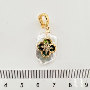 Makro-Detail des Barockperlen-Anhängers mit goldenem Kleeblatt und Stern auf Lineal