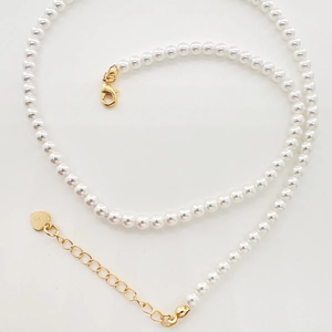 Detailed view of elegant white pearl necklace featuring gold lobster clasp and heart pendant