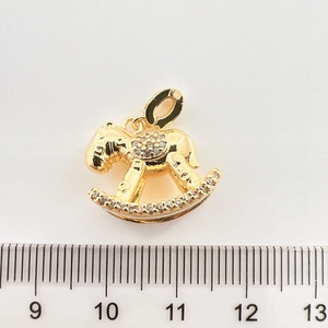 Détail du pendentif cheval à bascule doré avec incrustations de zircon et règle