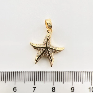 Détail d'un pendentif étoile de mer plaqué or avec zircons blancs et une règle