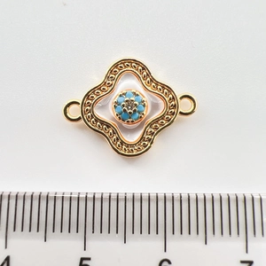 Detailed view of 18k gold plated four-leaf flower connector with turquoise and zircon
