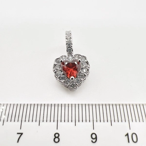 Detail shot showing heart pendant width measurement of 1cm with red gemstone