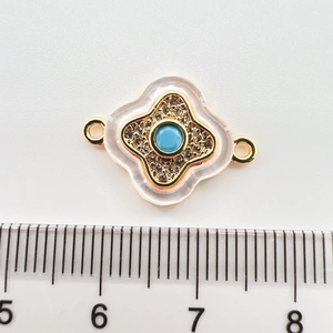 Detailed view of 18k gold plated floral connector charm with turquoise center and crystals