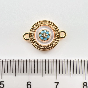 Macro view of 18k gold plated round pendant with turquoise beads and zircon floral detail