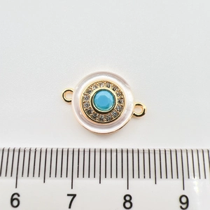 Macro detail of a round 18k gold turquoise charm with crystals and dual connectors