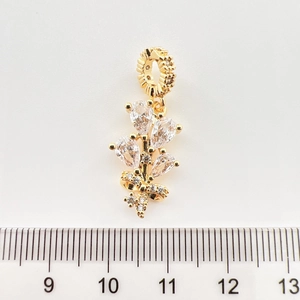 Détail d'un pendentif fleur doré avec zircons et règle pour indiquer la taille