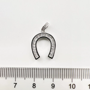 Détail d'un pendentif fer à cheval de 1,5 cm serti de zircons sur fond blanc épuré