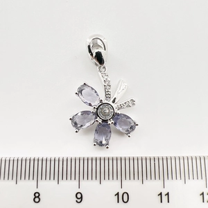 Vue détaillée d'un pendentif papillon doré avec pierres violettes et zircone près d'une règle