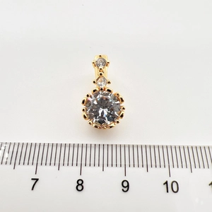 Macro view of gold pendant with round clear zircon stones and measurement scale