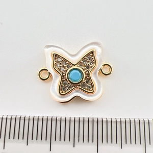 Macro view of gold-plated butterfly connector with turquoise center and shell wings