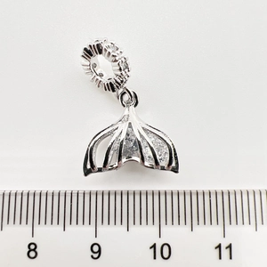 Gros plan d'un pendentif queue de sirène en argent avec zircons et règle de mesure