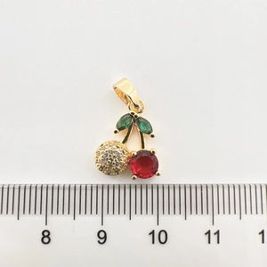Vue macro d'un pendentif cerise plaqué or avec des cristaux de zircone rouges et verts